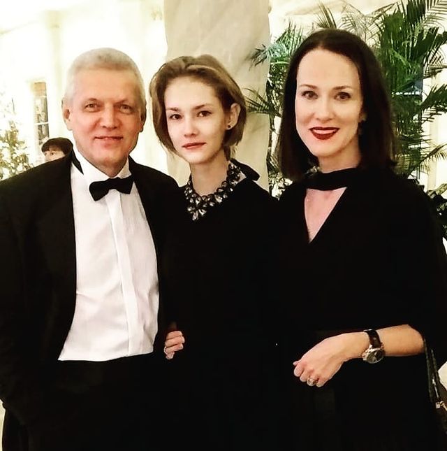 Aleksandr Galibin in a white shirt and black suit with his wife and daughter in black dress.